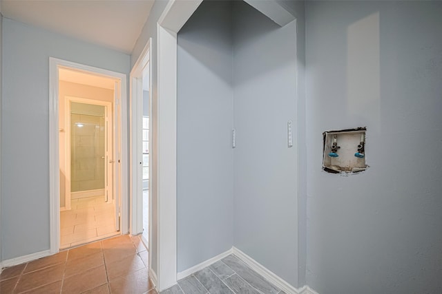corridor with light tile patterned flooring and baseboards