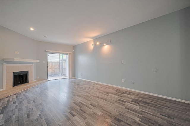 unfurnished living room featuring baseboards, a tiled fireplace, and wood finished floors