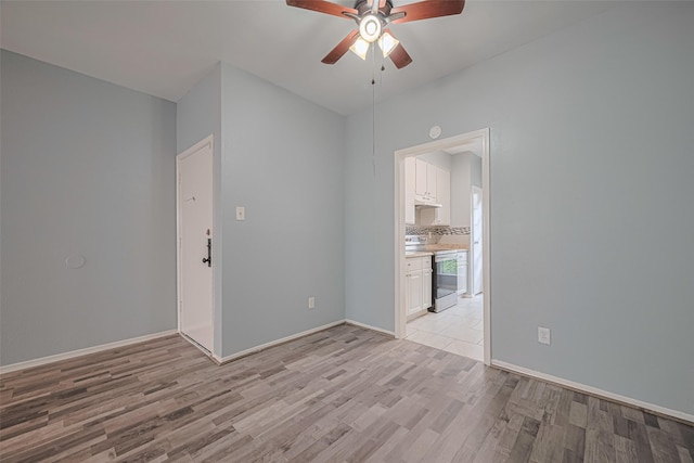 empty room featuring baseboards, ceiling fan, and light wood finished floors