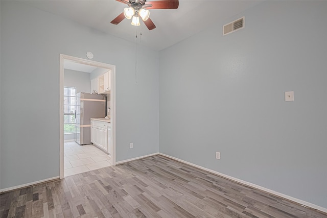 unfurnished room featuring visible vents, light wood-style floors, ceiling fan, and baseboards