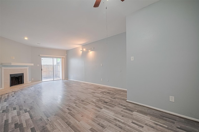 unfurnished living room with wood finished floors, baseboards, ceiling fan, recessed lighting, and a tiled fireplace