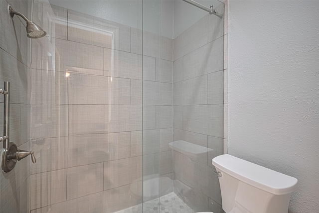 bathroom featuring toilet and a stall shower