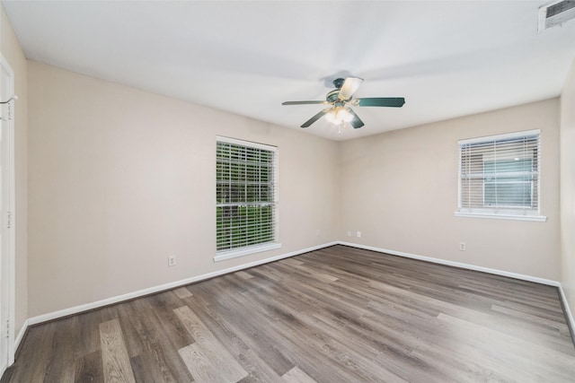 spare room featuring baseboards, a ceiling fan, wood finished floors, and visible vents