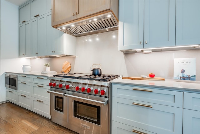 kitchen featuring light countertops, wood finished floors, extractor fan, and range with two ovens