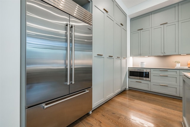 kitchen featuring light wood-style flooring, built in refrigerator, and light countertops