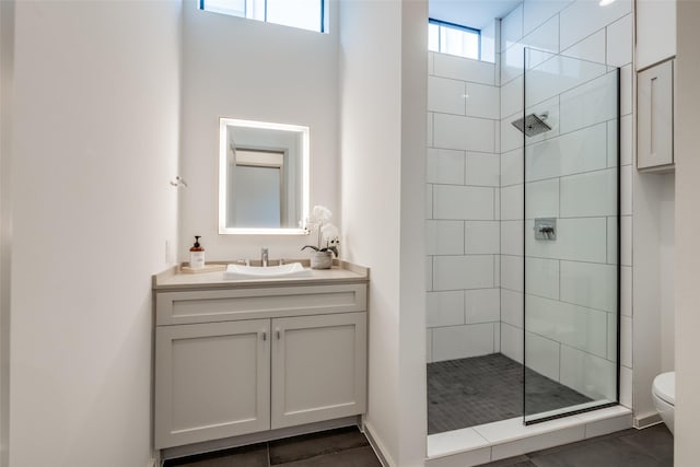 full bathroom with vanity, tile patterned flooring, a tile shower, and toilet
