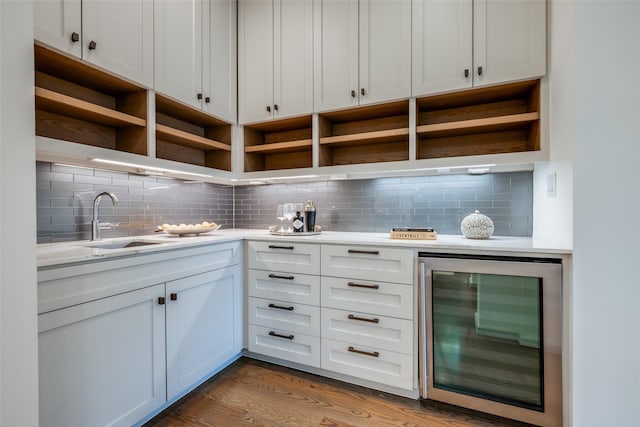 bar with a sink, decorative backsplash, beverage cooler, and wood finished floors