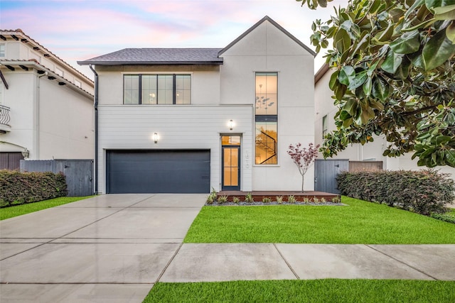 view of front of house featuring an attached garage, a lawn, stucco siding, and driveway