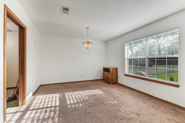 spare room featuring baseboards, carpet flooring, a chandelier, and visible vents