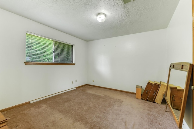carpeted spare room with a textured ceiling and baseboards
