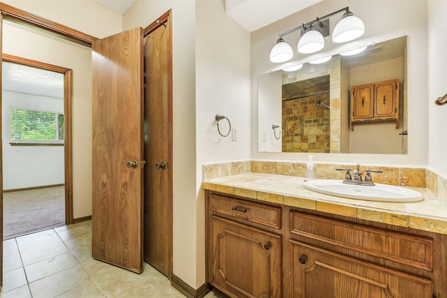 bathroom with tile patterned floors, tiled shower, and vanity