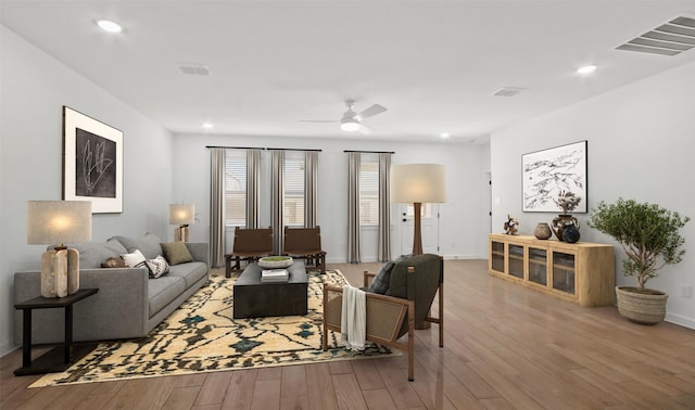 living room featuring a ceiling fan, visible vents, and wood finished floors