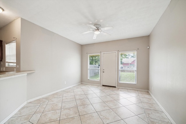 spare room featuring light tile patterned flooring, ceiling fan, and baseboards