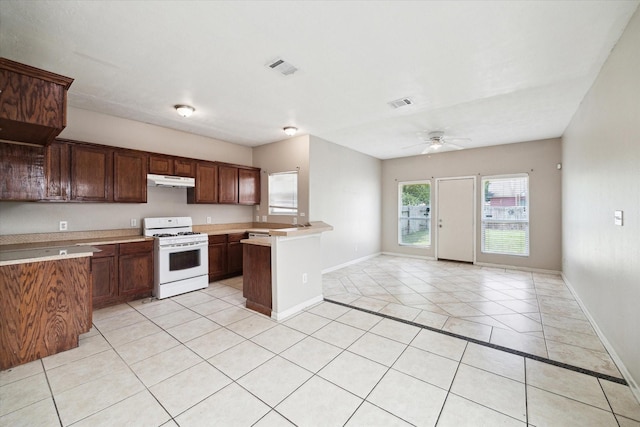 kitchen featuring a ceiling fan, light countertops, baseboards, under cabinet range hood, and white range with gas stovetop