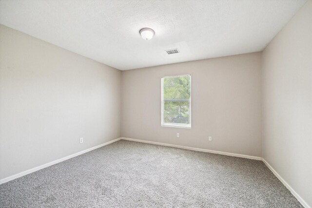 carpeted empty room featuring baseboards and visible vents