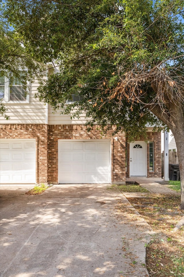 view of front of house with brick siding, an attached garage, and driveway