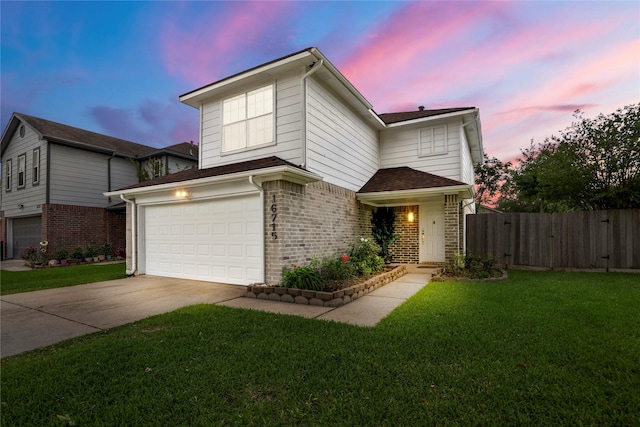 traditional home with driveway, brick siding, fence, a yard, and an attached garage
