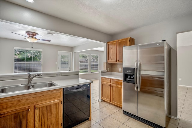 kitchen featuring stainless steel fridge, a sink, light countertops, black dishwasher, and light tile patterned floors
