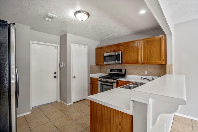 kitchen featuring visible vents, appliances with stainless steel finishes, a sink, light countertops, and a peninsula