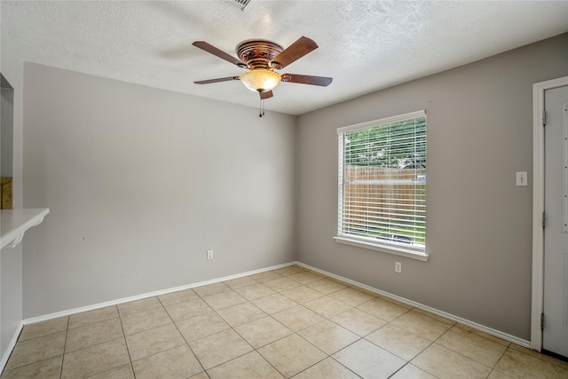 empty room with baseboards, a textured ceiling, ceiling fan, and light tile patterned flooring