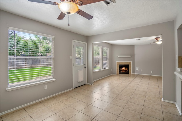 unfurnished living room featuring a fireplace, a ceiling fan, baseboards, light tile patterned floors, and visible vents