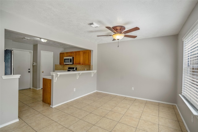spare room with a textured ceiling, ceiling fan, plenty of natural light, and light tile patterned floors