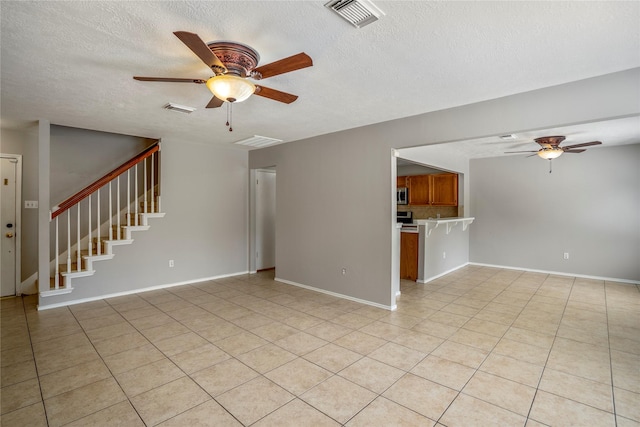 unfurnished living room featuring a ceiling fan, a textured ceiling, visible vents, and light tile patterned flooring