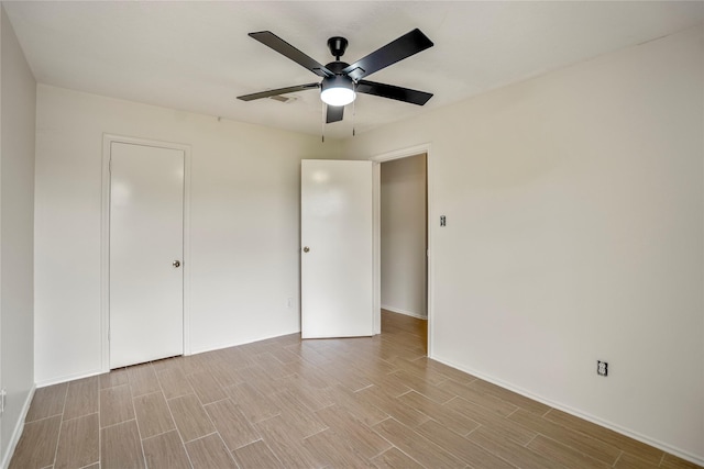 unfurnished bedroom with light wood-type flooring, a ceiling fan, and baseboards