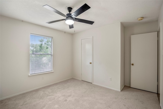 unfurnished bedroom featuring baseboards, light carpet, and a ceiling fan