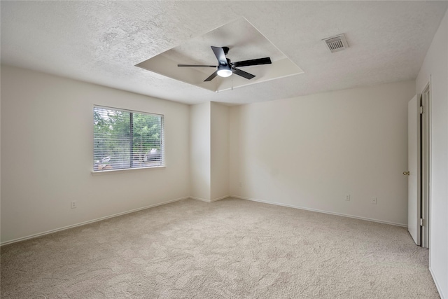 spare room featuring ceiling fan, carpet flooring, a textured ceiling, and visible vents