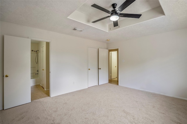 unfurnished bedroom featuring carpet floors, a textured ceiling, baseboards, and visible vents
