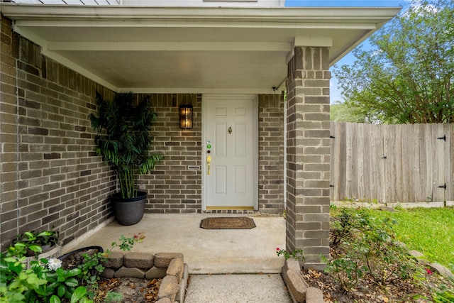 doorway to property with brick siding and fence