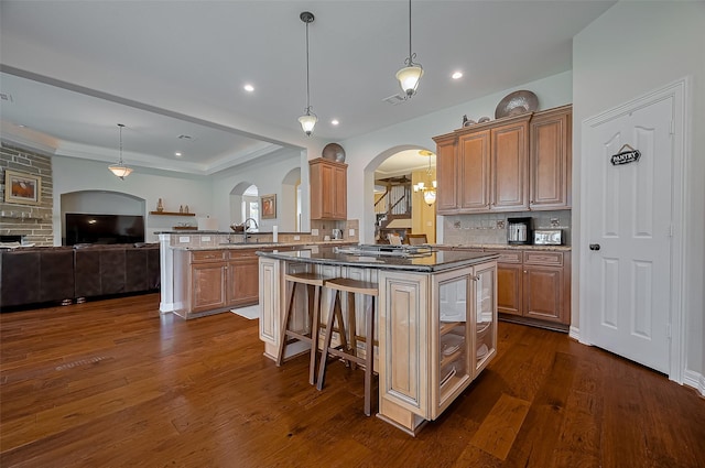 kitchen featuring dark wood-style flooring, arched walkways, a sink, and dark stone countertops