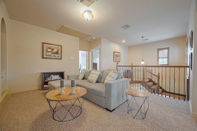 living room featuring visible vents, attic access, carpet, and arched walkways