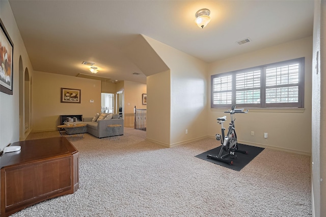 exercise area with visible vents, attic access, carpet, and baseboards