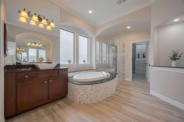 full bathroom with a bath, a stall shower, wood finished floors, vanity, and baseboards