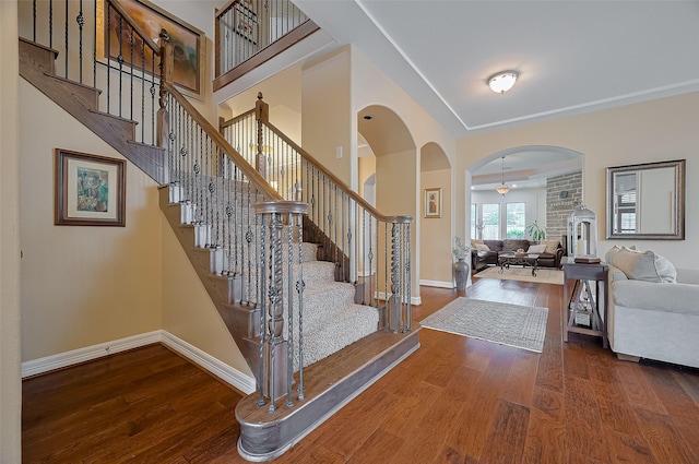 foyer with baseboards, arched walkways, stairs, and wood finished floors