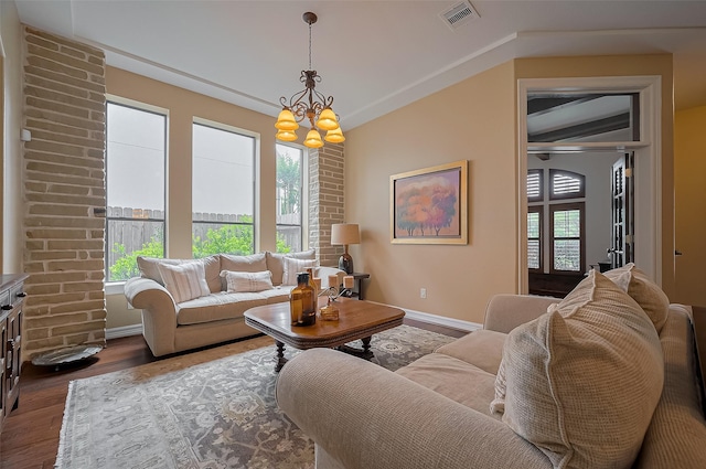 living room featuring an inviting chandelier, baseboards, wood finished floors, vaulted ceiling, and visible vents