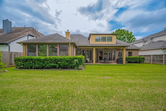 back of property with brick siding, a patio area, fence, and a lawn