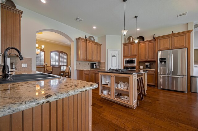 kitchen featuring decorative backsplash, arched walkways, a sink, dark wood finished floors, and appliances with stainless steel finishes