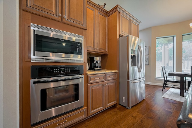 kitchen featuring brown cabinets, stainless steel appliances, baseboards, and dark wood-style floors