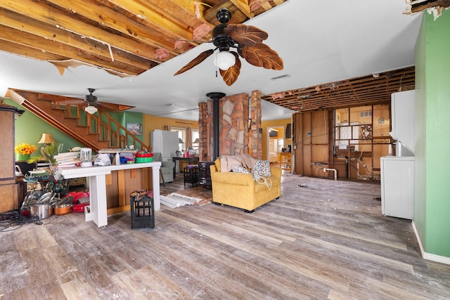 13114 Coronado Dr, Freeport, TX 77541 - living area with a ceiling fan, visible vents, a wood stove, wood finished floors, and stairway