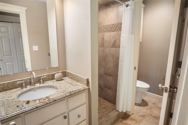bathroom featuring vanity, tile patterned floors, a tile shower, and toilet