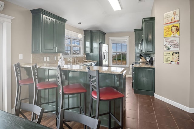 kitchen with a peninsula, a breakfast bar, baseboards, tasteful backsplash, and stainless steel appliances