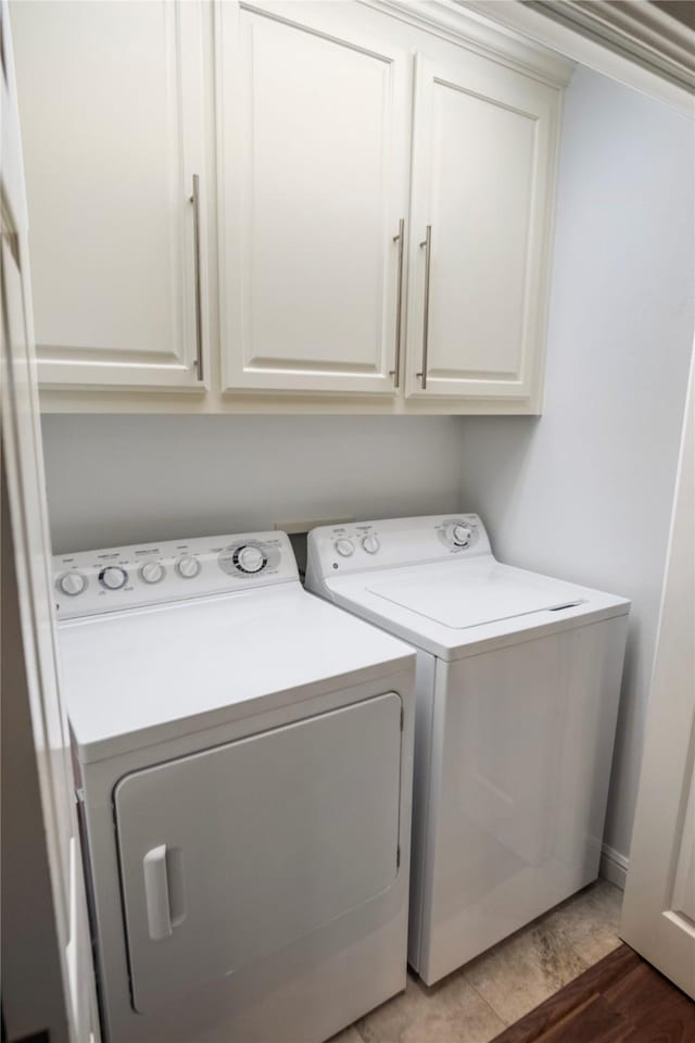 laundry area with light wood-style flooring, cabinet space, and washing machine and dryer