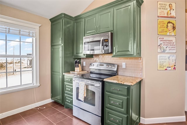 kitchen featuring baseboards, decorative backsplash, green cabinets, and stainless steel appliances