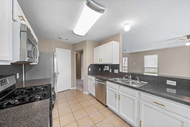 kitchen with white cabinets, dark countertops, a sink, stainless steel appliances, and visible vents