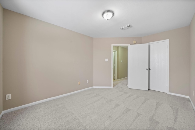 unfurnished bedroom with a closet, baseboards, light colored carpet, and visible vents