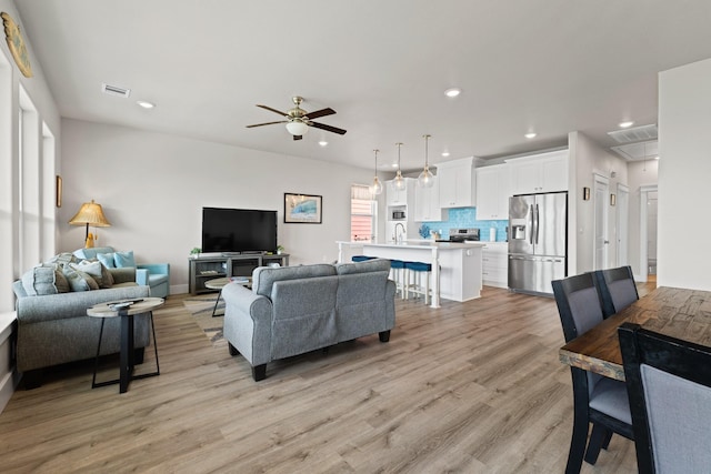 living room featuring visible vents, baseboards, recessed lighting, light wood-type flooring, and a ceiling fan
