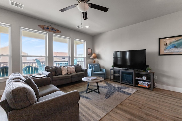 living room featuring ceiling fan, visible vents, and wood finished floors